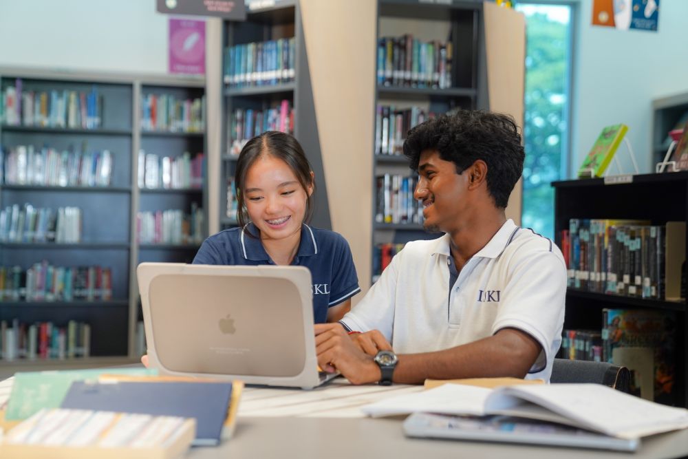 International school students working together on Extended Essay research in a library